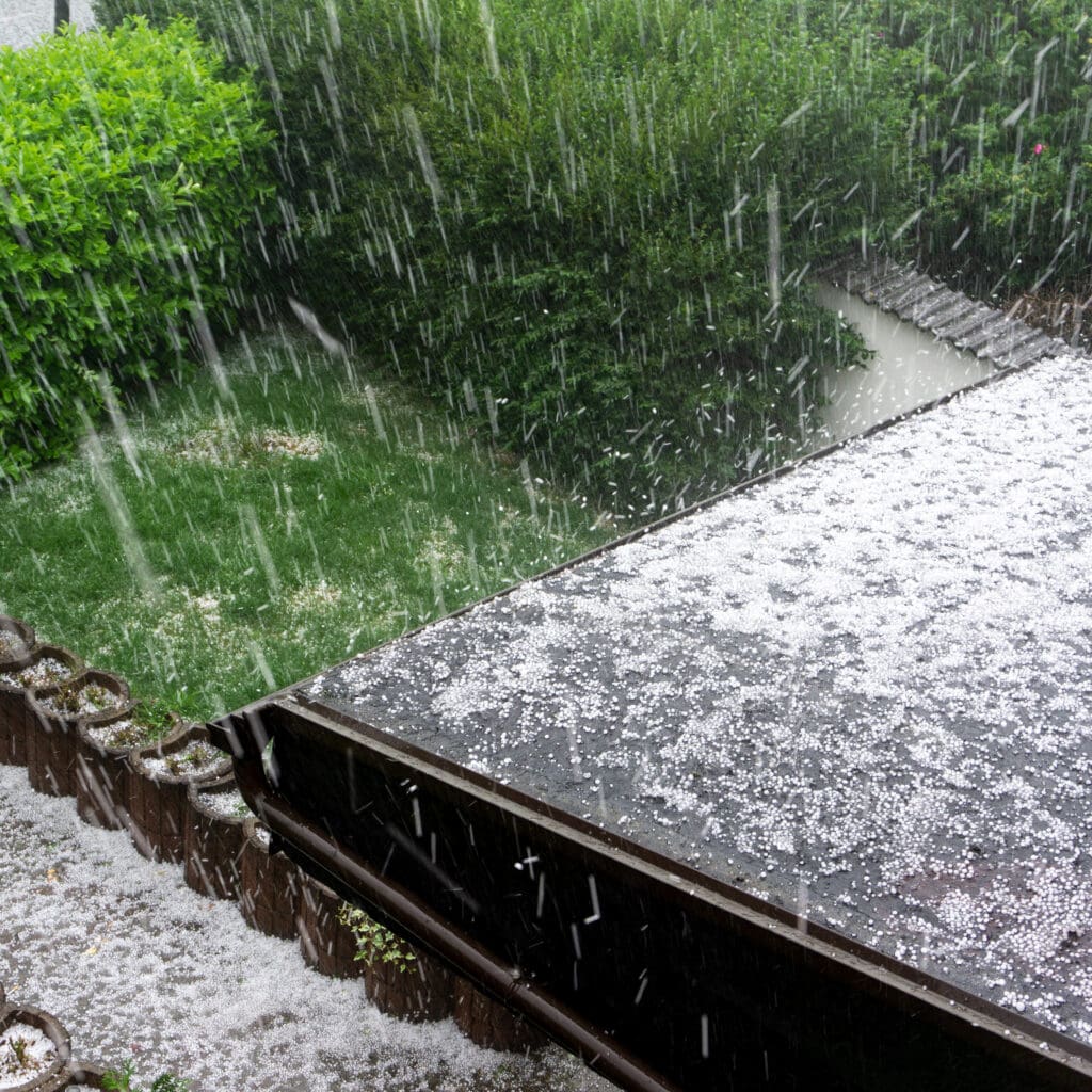 Hail falling on the roof of a residential home during a hailstorm.