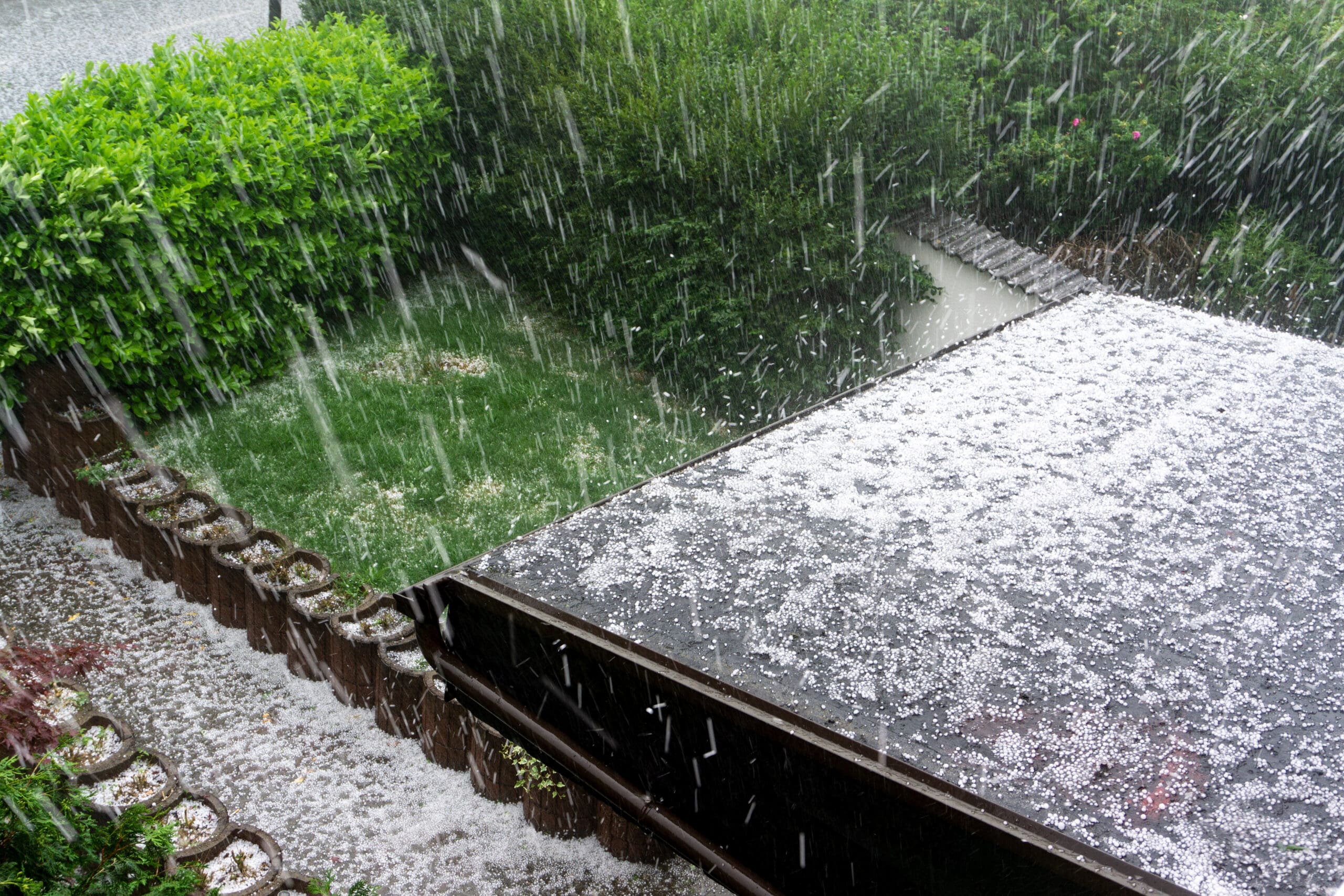 Hail falling on the roof of a residential home during a hailstorm.